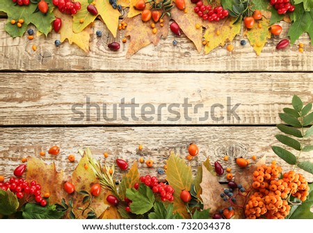Autumn leafs with berries on brown wooden table
