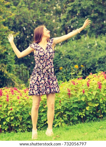 Happiness and carefree concept. Young woman having fun blowing soap bubbles outdoor in park