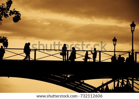 Paris. Silhouettes of  people on the bridge at sunset. Conciergerie at background. Sepia.
