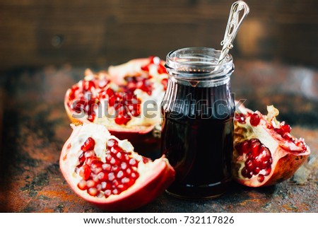 Pomegranate sauce in glass bottle over rustic background.