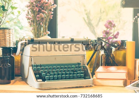 Vintage typewriter, ornaments, books and vases of flowers on a wooden table 