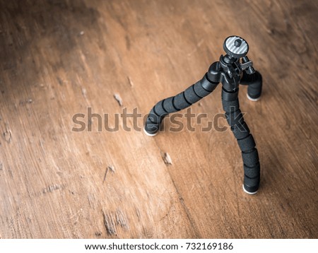 Small tripod on wood background. Selective focus.