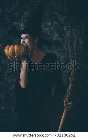 Halloween Witch holding a pumpkin and a broom. woman dressed like a fairy witch