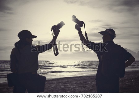 Sweet couple holding camera on the beach at sunset.