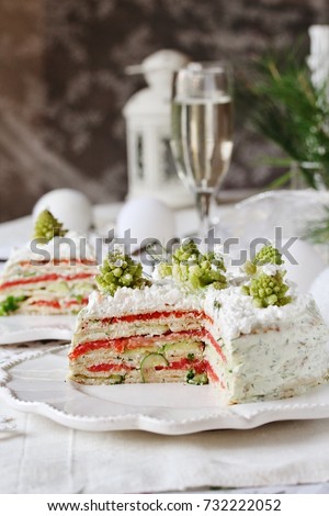 appetizer for Christmas or New Year. snack cake of pancakes with trout, avocado, cucumber, cheese. Decorated with Romanesco broccoli in the form of Christmas trees and cottage cheese as snow.