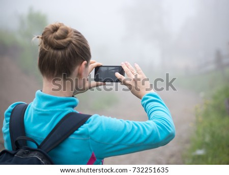 Young girl taking picture of wild place by smartphone