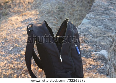 backpack on the edge of a cliff with ocean on the background at a autumn evening during a hiking session