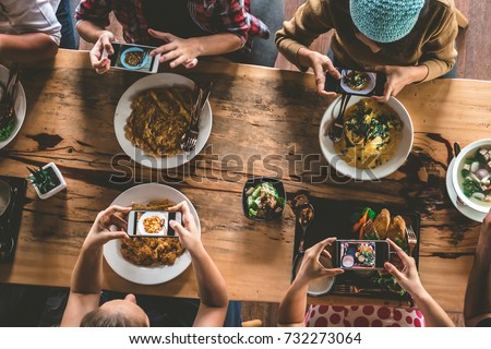 Group of friend take a picture with mobile phone before having nice food and drinks, enjoying the party and communication, Top view of Family gathering together at home for eating dinner.