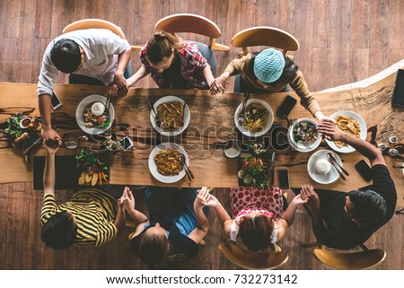 Group of friend pray before having nice food and drinks, enjoying the party and communication, Top view of Family gathering together at home for eating dinner. Royalty-Free Stock Photo #732273142