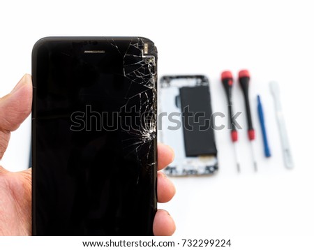 Close-up of cracked smartphone screen in technician hand on blurred smartphone component background with copy space