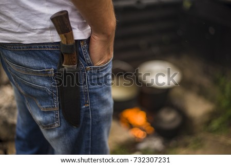 knife in the case attached to the human strap close-up. a man carries a dagger in his holster with his hand in his pocket. security for tourists cold steel from a predator. Royalty-Free Stock Photo #732307231