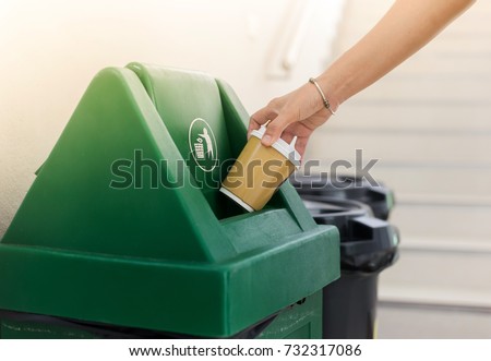 Closeup woman hand throwing empty paper coffee cup in recycling bin. Royalty-Free Stock Photo #732317086