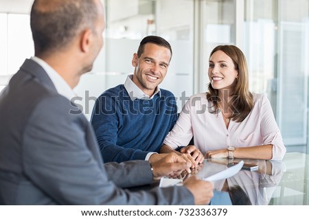 Mature financial advisor showing report to young couple for their investment. Salesman and positive couple talking about purchase. Happy couple consulting financial agent for loan. Royalty-Free Stock Photo #732336379