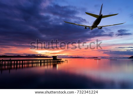 Commercial airplane flying above clouds with dramatic sunset or sunrise sky and light background