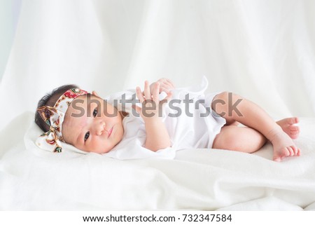 Cute infant baby sleeping and looking on bed with white bed sheets background concept International Day of the Girl Child, apple of the eye, Christian baptism newborn baby  