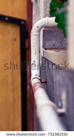 White Pipe line with wine red paint spots beside a house exterior