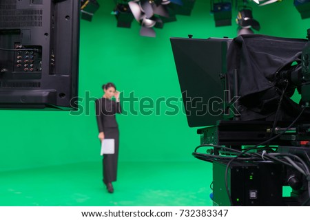 Blur image of television announcer in broadcast green screen studio room with professional camera and LED lights on the ceiling.