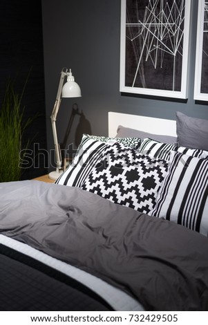 Bed with pillows in the bedroom near black wall. Interior in black and white colors