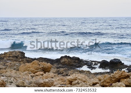 Morning sunrise on the beach. Wild rocky beach. Natural rock formations covered with sparse Alpine vegetation. Surfing in the summer on the rocky coast of the island.