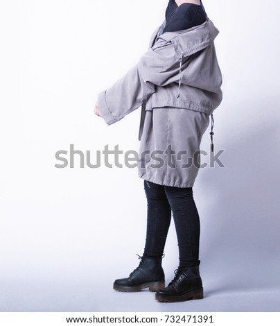 Woman wearing casual outfit with oversized parka jacket, black skinny jeans and black boots isolated on white background. Copy space
