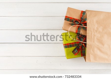 Handmade new year gifts in paper bag on white wood table background. Boxes with satin ribbons for christmas, valentine day or birthday. Copy space, top view