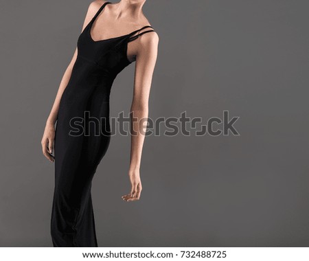 Young Woman Leaning in Black Dress on Gray Background