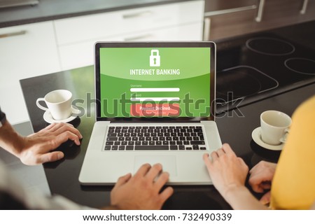 Internet banking text on log in display against couple using laptop in kitchen