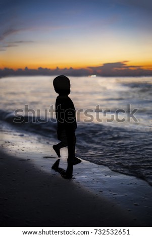 Image of kid playing in the beach in a beautiful sunset. summer, back light, blue sea