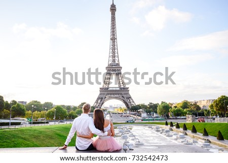 Couple in Paris sitting on the rooftop hugging and  looking at the Eiffel tower