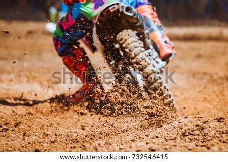 Details of flying debris during an acceleration with mountain bikes race in dirt track in sunshine day time in blurry background. Concept of focus between an accelerate in action sport