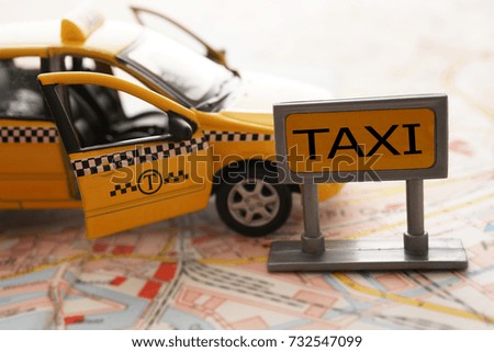 yellow taxi car stand on paper man with signboard with word - taxi. toy model. open doors. standing sign
