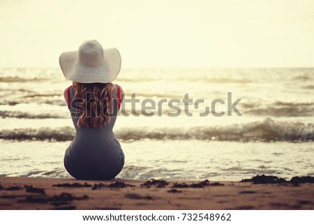 Silhouette of young woman on beach with hat