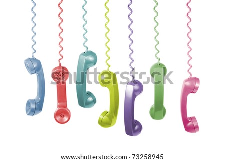 Lots of different coloured old phone handsets are hanging on white background Royalty-Free Stock Photo #73258945