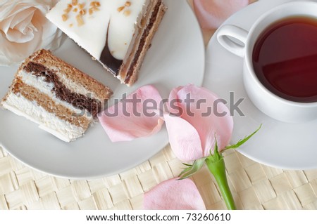 Closeup of cake with romantic roses and cup of tea