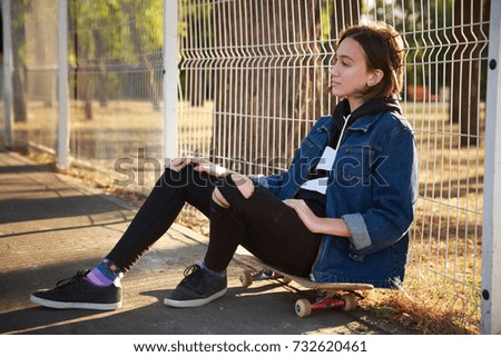 A girl is sitting on a skateboard in the park.