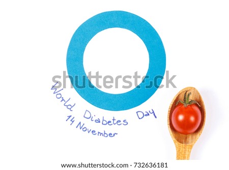 Fresh tomato on wooden spoon and blue circle of paper as symbol of world diabetes day and fighting disease, concept of healthy nutrition