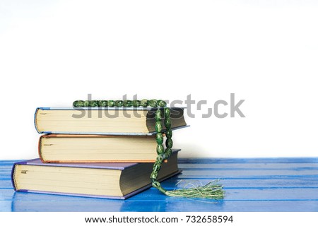 Close up hardcover book with tasbih or breads isolated on white background. Holy spirituality book concept. Selective focus.