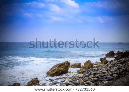 Landscape South China Sea. Asian theme with rocky beach and Chinese fishing junks in background under blue skies with puffy clouds. 