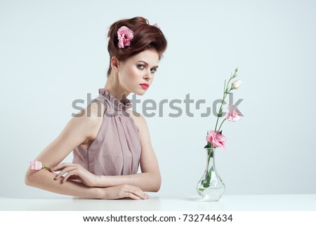 lady with a hairstyle, vase with a flower branch on a light background                               