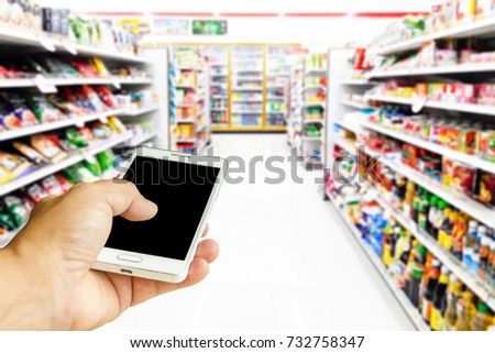 Man use mobile phone, blur image of inside the convenience store as background.