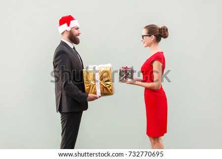 Happiness couple looking each other and holding gift box. Studio shot. Gray wall