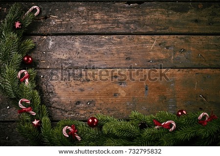 Christmas border of green pine foliage and candy canes on rustic wood with copy space