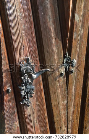 Photo taken in Bratislava. On the photo, an artfully made door handle on an old wooden door.