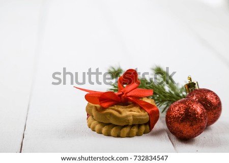 Christmas cookie with a red bow, spruce branch and balls. Beautiful still life on a wooden table.