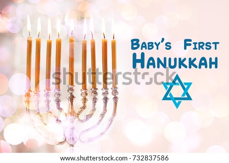 Beautiful menorah with burning candles for baby's first Hanukkah on blurred background