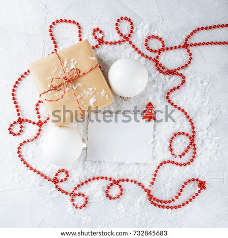 Christmas gift boxes in kraft paper, red beads and a congratulatory crochet on snow-covered background. Top view