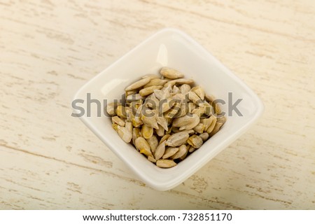 Peeled sunflower seeds heap over the wooden background