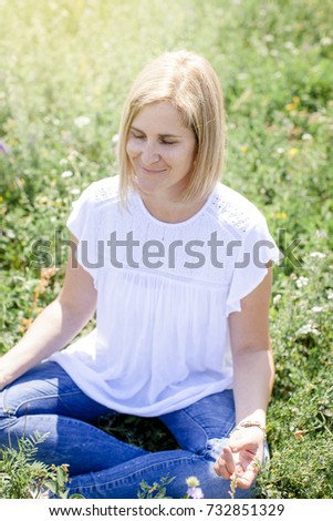 Happy woman is doing yoga in the meadow