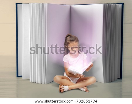 Cute tiny girl reading fairy tale near giant book on table