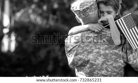 Happy reunion of soldier with family, son hug father. Black and white emotional portrait of american soldier father and his son